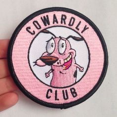 a hand holding a pink patch with the words cowrolly club in black and white