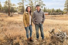 a man and woman standing next to each other in the middle of an open field