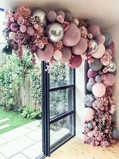 the balloon arch is decorated with pink and grey balloons, flowers and greenery for an outdoor party