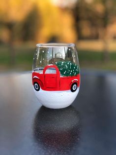 a glass with a red truck painted on it sitting on top of a black table