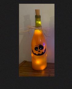 a lighted bottle with a pumpkin face on it