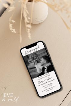 an iphone case with a wedding photo on it sitting next to a vase and flowers