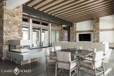 a dining room table and chairs in front of a stone wall with an open fireplace