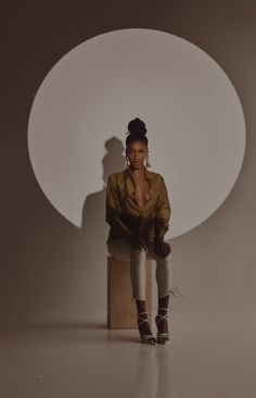 a woman sitting on top of a wooden chair in front of a white circle wall