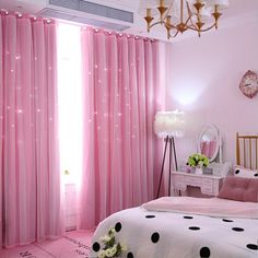 a bedroom decorated in pink and black with polka dots on the bed, chandelier