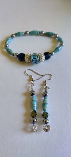 a necklace and earring set made from glass beads with silver accents on a white surface