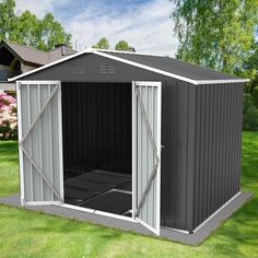 a small gray shed sitting on top of a lush green field