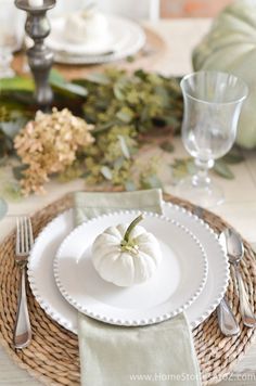 a white pumpkin sitting on top of a plate next to silverware and napkins