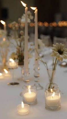 candles are lit on a table with flowers in vases