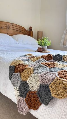 a crocheted blanket on top of a bed in a room with a wooden headboard