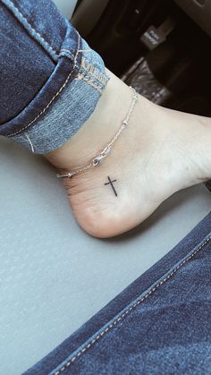 a woman's foot with a small cross tattoo on the side of her ankle