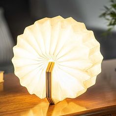 a table lamp sitting on top of a wooden table next to a vase filled with flowers