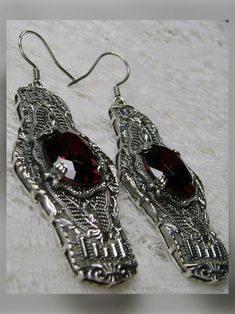 Red Garnet Solid Sterling Silver Earrings Oval Castle Design#E4 Inspired by the Art Deco movement of the early 1900s, this is a pair of Art Deco antique reproduction earrings in sterling silver. The flawless red garnet gems are surrounded by delicate sterling silver filigree. The lovely 7.54 carat oval stones are approximately 14mm by 10mm in length & width. The gemstones have excellent color and clarity. The earrings are 2-1/2" long and are marked 925 for sterling silver. These elegant earrings Oval Metal Earrings For Wedding, Elegant Jeweled Oval Earrings, Elegant Oval Jeweled Earrings, Oval Metal Wedding Earrings, Oval Pierced Jewelry For Party, Red Jeweled Earrings For Gift, Nickel-free Oval Jewelry For Party, Red Embellished Earrings For Gift, Red Gemstone Earrings For Gift