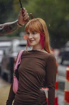 a woman with red hair holding an umbrella