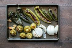 an assortment of vegetables on a baking sheet with garlic, peppers, and other foodstuffs