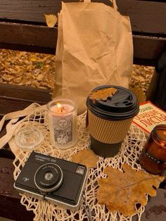 a table topped with a cup of coffee next to a brown bag and some other items