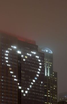 a very tall building with some lights on it's side in the city at night