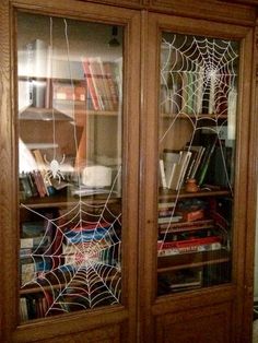 a book case with spider webs and books on it's glass front doors