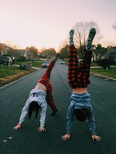 two people doing handstands on the street