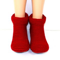 the legs of a doll wearing red knitted slippers