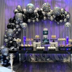 a table with silver and black balloons on it