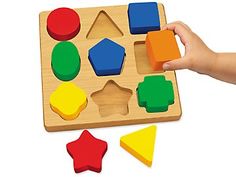 a child's hand playing with wooden shapes