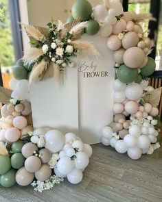 balloon arch with flowers and greenery on the side for a baby's shower