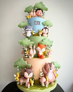 a three tiered cake decorated with animals and trees