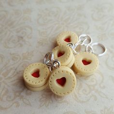 four white donuts with red heart holes on them are sitting on a lace tablecloth