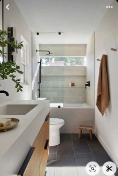 a bathroom with a toilet, sink and bathtub next to a plant in the corner