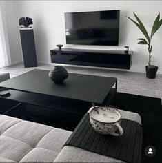 a modern living room with black and white furniture, large flat screen tv on the wall