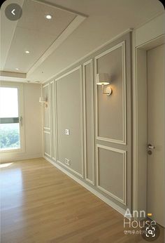 an empty room with wood floors and white walls, in front of a large window