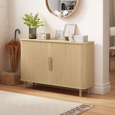 a wooden cabinet with a mirror on the wall above it and a potted plant next to it