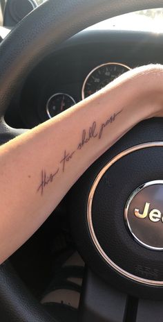 a person with a tattoo on their arm driving a car