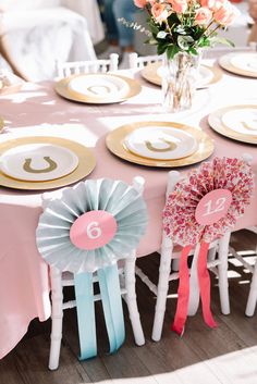 the table is set with pink, blue and gold ribbons on each chair for guests to sit at