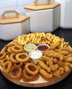 a wooden platter filled with onion rings and dipping sauces