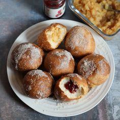 powdered sugar covered doughnuts on a plate next to a container of macaroni and cheese