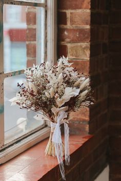 a bouquet of flowers sitting on top of a window sill next to a brick wall