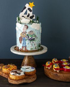 three cakes and cupcakes on wooden platters in front of a blue wall