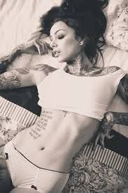 a woman laying in bed with tattoos on her stomach