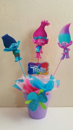 there are three little trolls in the cup and one is holding two toothbrushes