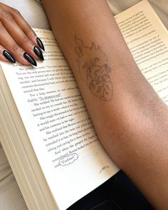 a woman's arm with a tattoo on it and an open book behind her