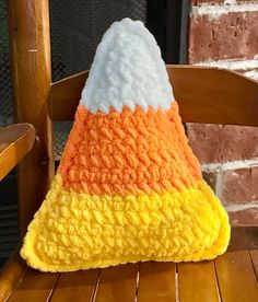 an orange, yellow and white knitted hat sitting on top of a wooden chair