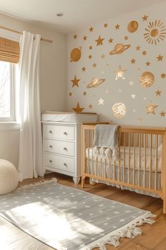 a baby's room decorated with gold stars and planets on the wall, along with a white crib