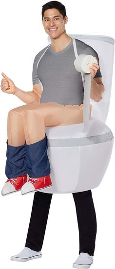 a man sitting on top of a white toilet with his legs crossed and thumbs up