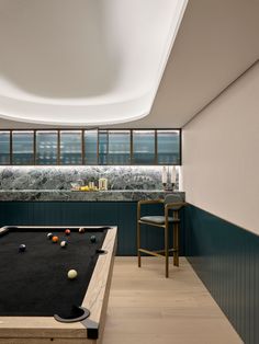 a pool table in the middle of a room with chairs and counter space behind it