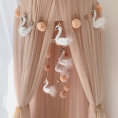 two white swans are hanging from the ceiling in front of a pink drapeed curtain