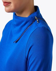 Experts in high-quality, everyday essentials, E.L.I. brings a relaxed, yet feminine attitude to all its pieces. This blue long sleeve tunic is made from pima cotton fabric and is finished with an elegant, zippered cowl neck. Style it with black pants and a leather bag for a comfortable and classic look. Long Sleeve Tops With Zipper Closure For Layering, Zipper Closure Long Sleeve Top For Layering, Long Sleeve Tops With Zipper Closure, Blue Stretch Half-zip Top, Blue Long Sleeve Top With Zipper Closure, Blue Funnel Neck Top For Layering, Modern Half-zip Tops For Fall, Blue Funnel Neck Tops For Spring, Blue Half-zip Top For Spring