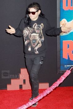 a man with long hair and sunglasses standing on a red carpet