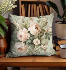 a pillow sitting on top of a wooden table next to a cup and potted plant